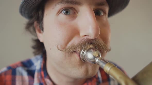 Cheerful Young Man with a Funny Mustache and a Hat Playing on the Big Tuba. 