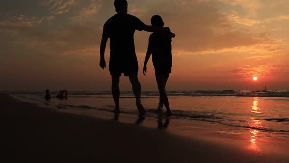 Father and Son Walk on the Beach at the Sunset Time