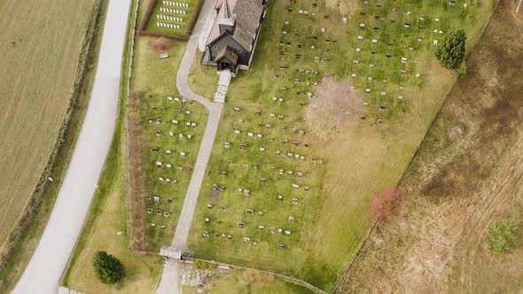 View Of Wooden Church With Graves In Sel Norway At Daytime - aerial drone shot alt