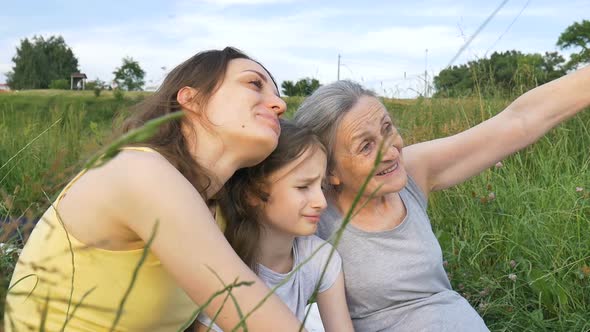 Cute Child Girl with Her Young Mother and Senior Grandmother are Having Picnic During Summer Outdoor alt