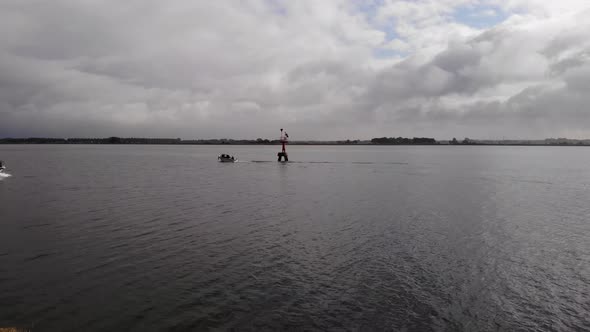 fishing boat and pleasure craft passing between the beacon of light on a fairway on a cloudy day in alt