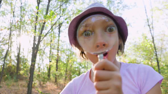 Cute Adorable Caucasian Girl Kid Looking at Camera in Forest Through Magnifying Glass alt