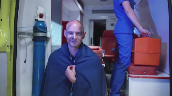 Man in Blanket Sit in Ambulance Car in Blanket and Smile alt