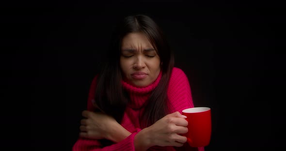 Brunette in a Pink Sweater is Frozen and Warms Up with a Hot Drink in a Red Mug