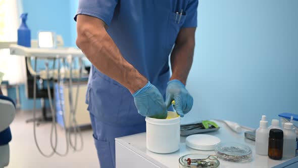 Dentist in Medical Blue Uniform Makes a Plaster or Silicone Material Cast of Set of Teeth Using