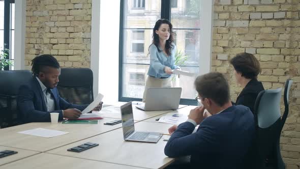 Confident Beautiful CEO Passing Documents To Colleagues and Talking. Portrait of Successful Young alt