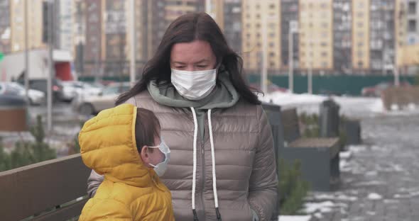 A Mother Puts Protective Mask on Herself and on Her Little Son