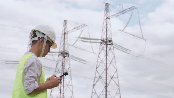 An Electrical Engineer Forcing a Drone To Inspect High Voltage Poles Before Starting a Project alt