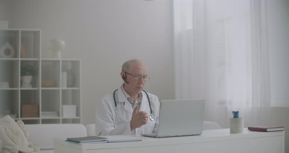 Male Experienced Virologist Is Lecturing Online, Using Laptop with Web Camera and Internet, Remote alt