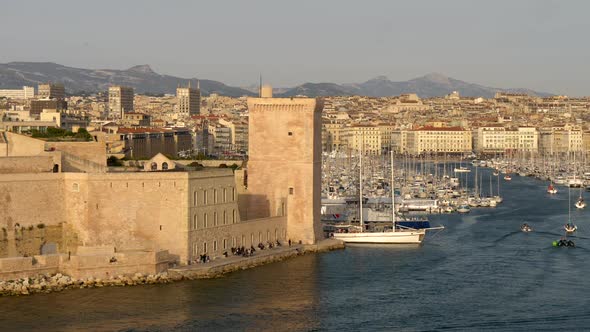 Marseille, France. Boats Sailing By the Old Port of Marseille. A Tower of Fort Saint-Jean Is Seen in alt
