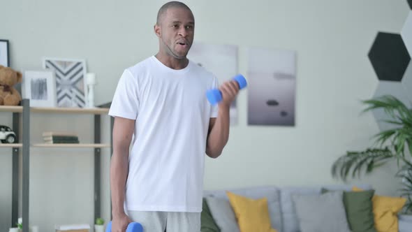 Sporty African Man Working Out with Dumbbells at Home alt