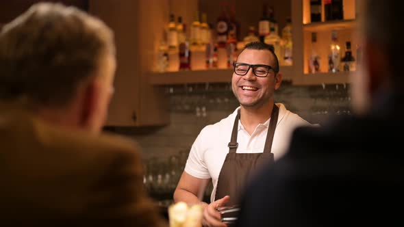 smiling and sociable bartender conducts a conversation with customers ...