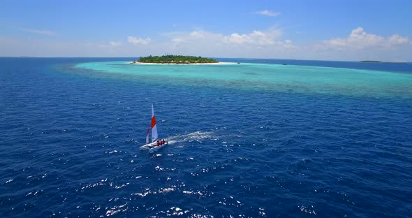 Aerial drone view of a man and woman sailing on a boat to a tropical island alt