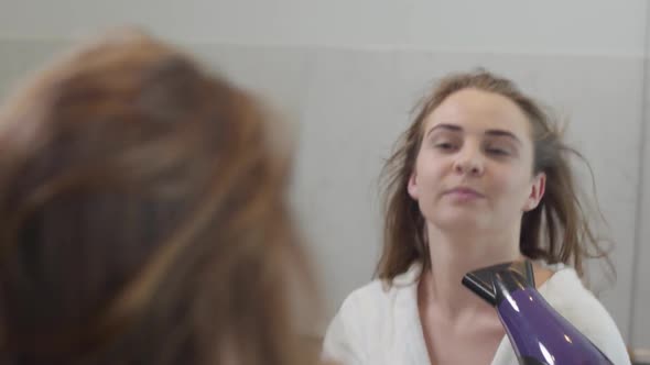 Portrait of Lovely Young Caucasian Woman Looking at the Camera and Dancing While Drying Her Hair alt