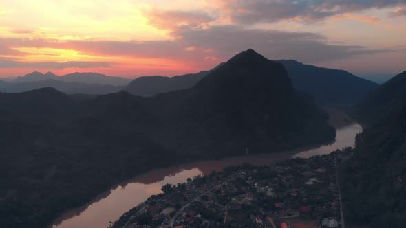 Aerial: flying over Nam Ou River Nong Khiaw Muang Ngoi Laos, sunset dramatic sky alt