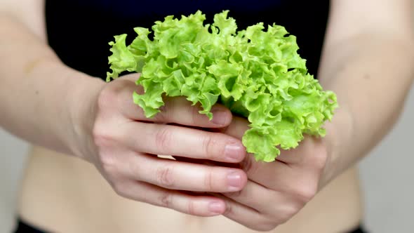 weight loss and healthy nutrition concept. fit woman is holding in hand green lettuce salad leaves.  alt