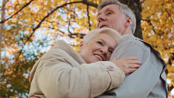 Married Caucasian Elderly Family Middleaged Couple Standing Outdoors in Autumn Park Hugging Gray alt