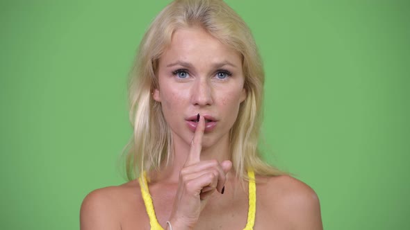 Young Happy Beautiful Blonde Woman with Finger on Lips