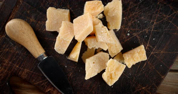 The Lumps of Parmesan Cheese on Cutting Board with Knife. 