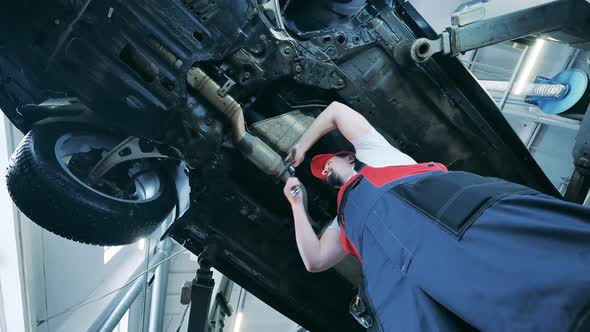 Bottom View of a Car Mechanic Fixing a Vehicle From Underneath alt