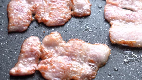 Crispy Pieces of Delicious Bacon are Fried in a Hot Pan alt
