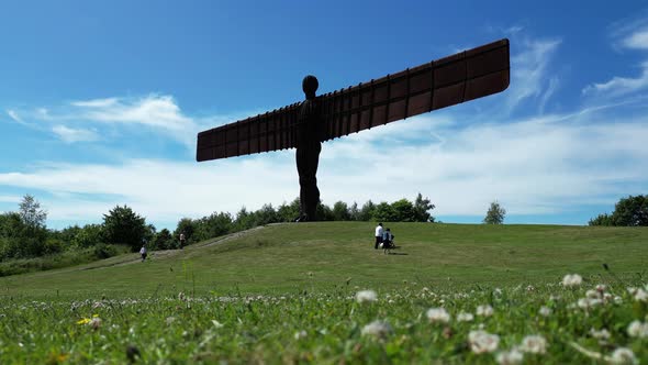 Angel of the North. Couple with pram walk along the front of the Angel Of The North in the North of alt