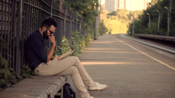 Man Reading Book On Train Station. Tourist Reading Book When Waiting Train On Electric Train Station alt