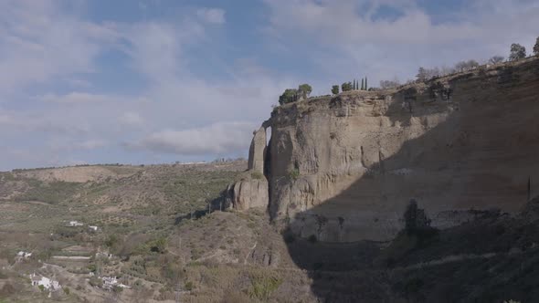 Aerial approaches nearly detached limestone pillar below Ronda, Spain alt