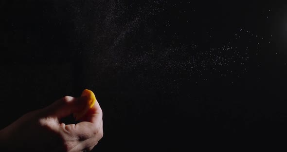 Female hand squeezes the skin of an orange on a black background