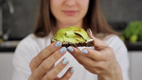 Extra Close Up Young Woman Unrecognizable Holding and Rotating Sandwich with Avocado at Home alt