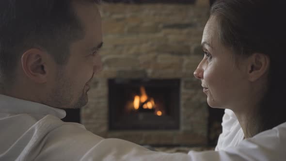 A couple in love is kissing by the fireplace, in which a fire is burning alt