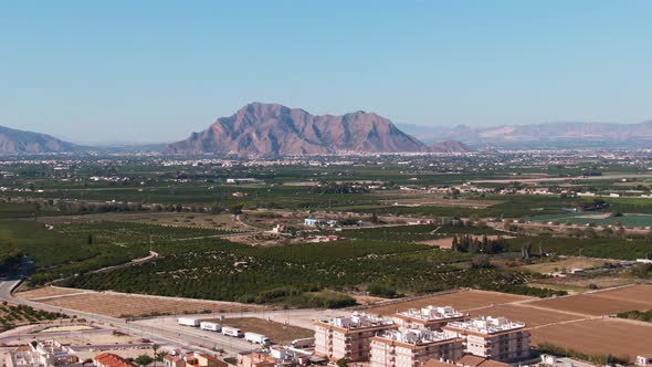 Buildings, Green Citrus Farm Fields, And Mediterranean Mountainscape Near Algorfa, Spain. alt