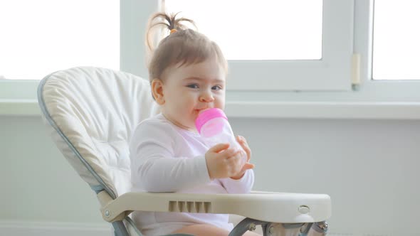 Cute Baby Girl Playing with Plastic Spoon Near the House Window alt
