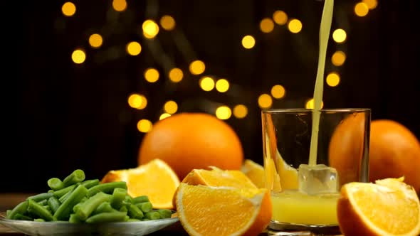 A Few Slices And A Whole Orange And Juice Are Poured Into A Glass And Green Beans With Lights