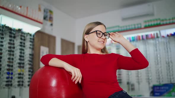 Lovely girl trying on new glasses at optics.  alt