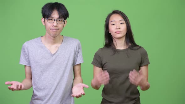 Young Asian Couple Shrugging Together