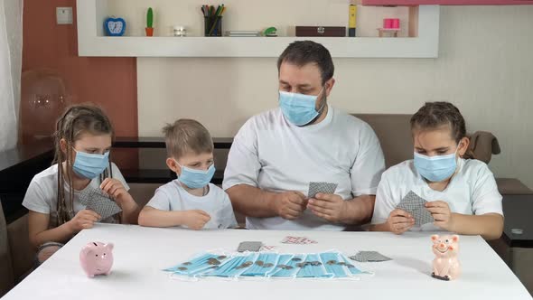 Dad with Children in Medical Masks Playing Cards, Social Distancing and Self-isolation 