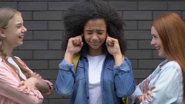 Biracial Teenage Girl Covering Ears From Bullying, Mockery of Classmates, Racism alt