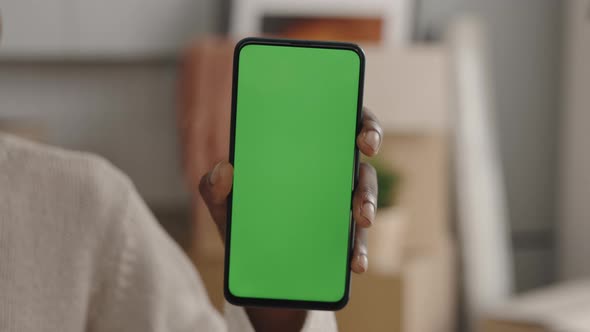 Closeup of African American Female Hand Holding Green Chroma Key Screen Smartphone Indoors in Light alt