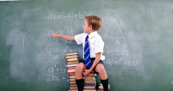 Schoolboy solving maths formula on chalkboard alt