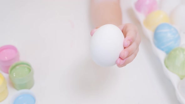 Macro a Child's Hand Holds a White Chicken Egg and Begins to Paint It Yellow alt