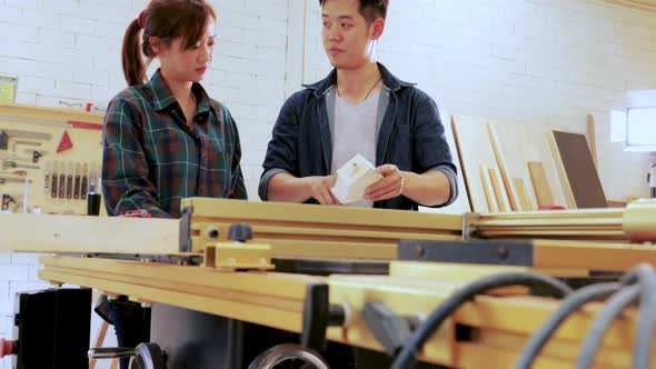 Couple Carpenter workers designing construction for built-in furniture project in workshop