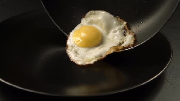 Taking out of a fried eggs from the pan to the dish