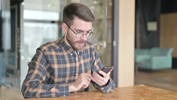 Young Designer Getting Success on Smartphone in Office alt
