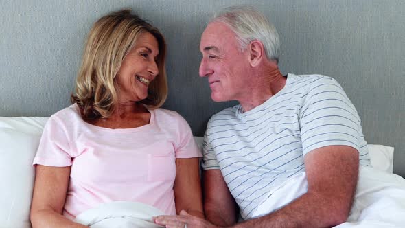 Senior man giving gift to woman in bedroom alt