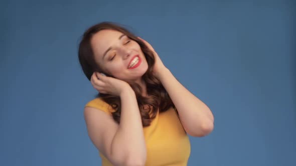 Jovial Young Woman Dancing While Listening To Music in Headphones