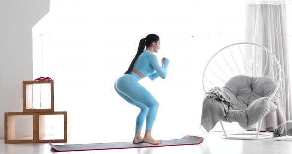 Young athletes woman in sportswear doing squat at home.