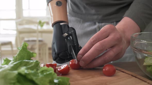 Handicapped Man with Bionic Forearm Cutting Cherry Tomatoes alt