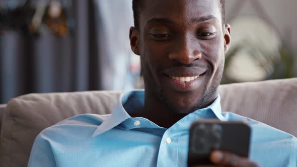 Smiling businessman sending messages using smartphone on the couch alt
