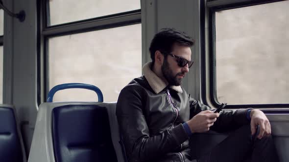Man In Sunglasses Using Mobile Phone On Train. Businessman Chatting On Mobile Phone Sending Message. alt